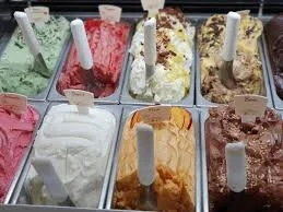 Tubs of colorful ice cream flavors in a shop display case